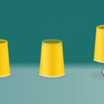 Image of a trio of vibrant yellow cups, concealing a mysterious ball beneath one.