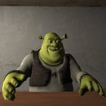 Image of Shrek, the iconic ogre from the DreamWorks animated film, looking up with a mischievous grin. He is wearing a brown vest and has his hands placed on a wooden table. The background suggests a dimly lit room with a grey wall. Shrek's expression hints at a playful or possibly sinister demeanor, leaving the viewer to wonder about his intentions in this particular scene.