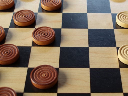 Image of a checkerboard pattern on a wooden table, ready for a game of Checkers unblocked