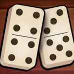 Image of two dominoes, one with six dots on the left side and five dots on the right side, the other with six dots on the left side and six dots on the right side, lying on a wooden surface.